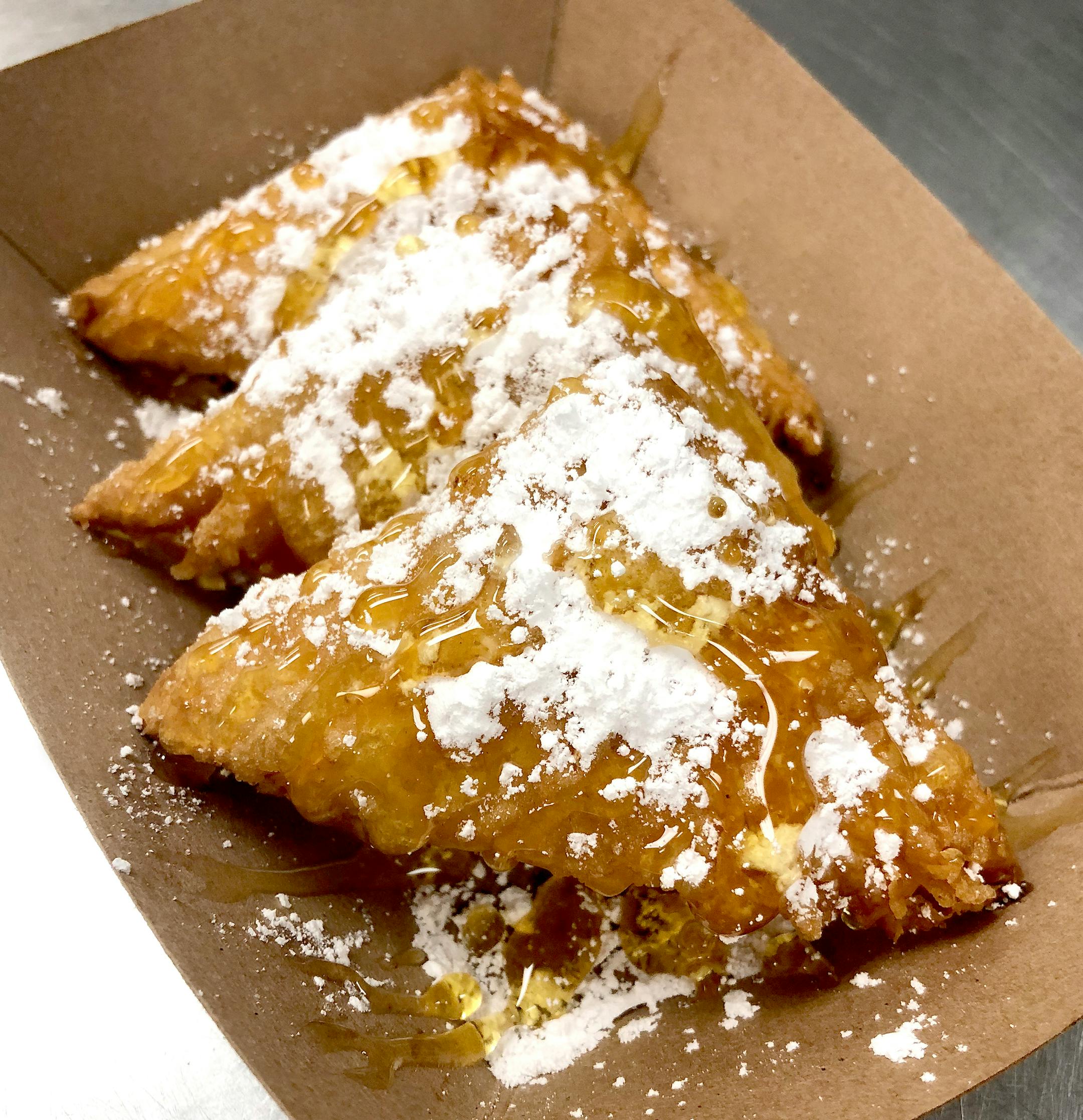 Sweet Greek Cheese Puffs: Flaky phyllo dough filled with feta and ricotta cheese, deep-fried, drizzled with honey and topped with powdered sugar. At Dino's Gyros, located on the north side of Carnes Av. between Nelson & Underwood streets.