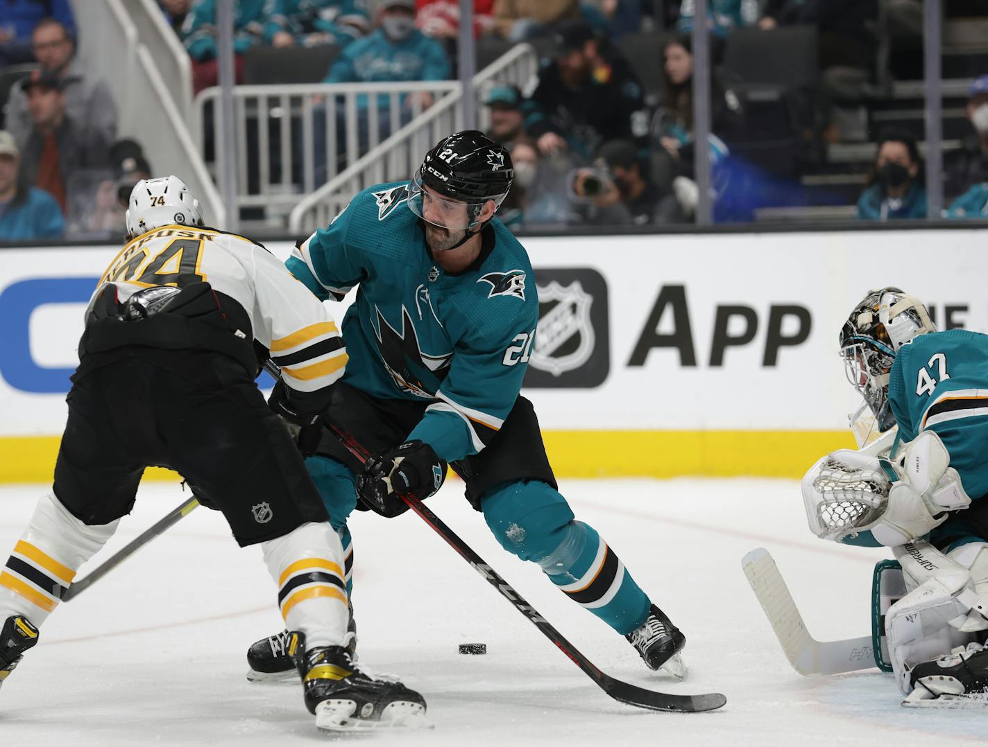 Boston Bruins left wing Jake DeBrusk (74) battles for the puck against San Jose Sharks defenseman Jacob Middleton (21) as Sharks goaltender James Reimer (47) defends in the second period of an NHL hockey game in San Jose, Calif., Saturday, Feb. 26, 2022. (AP Photo/Josie Lepe)