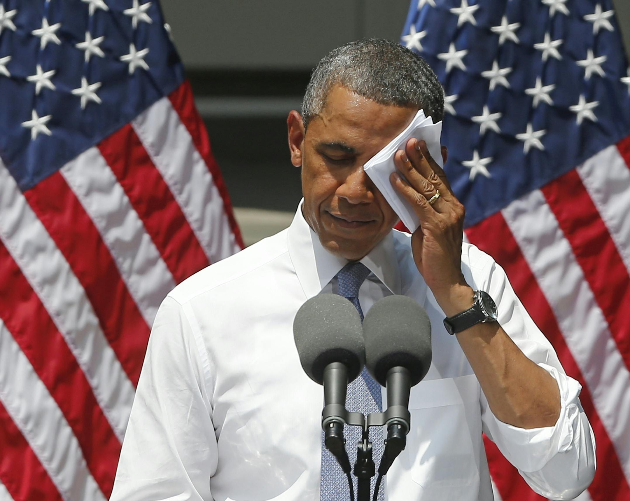 President Barack Obama wipes his face as he speaks about climate change, Tuesday, June 25, 2013, at Georgetown University in Washington. The president is proposing sweeping steps to limit heat-trapping pollution from coal-fired power plants and to boost renewable energy production on federal property, resorting to his executive powers to tackle climate change and sidestepping the partisan gridlock in Congress. (AP Photo/Charles Dharapak)