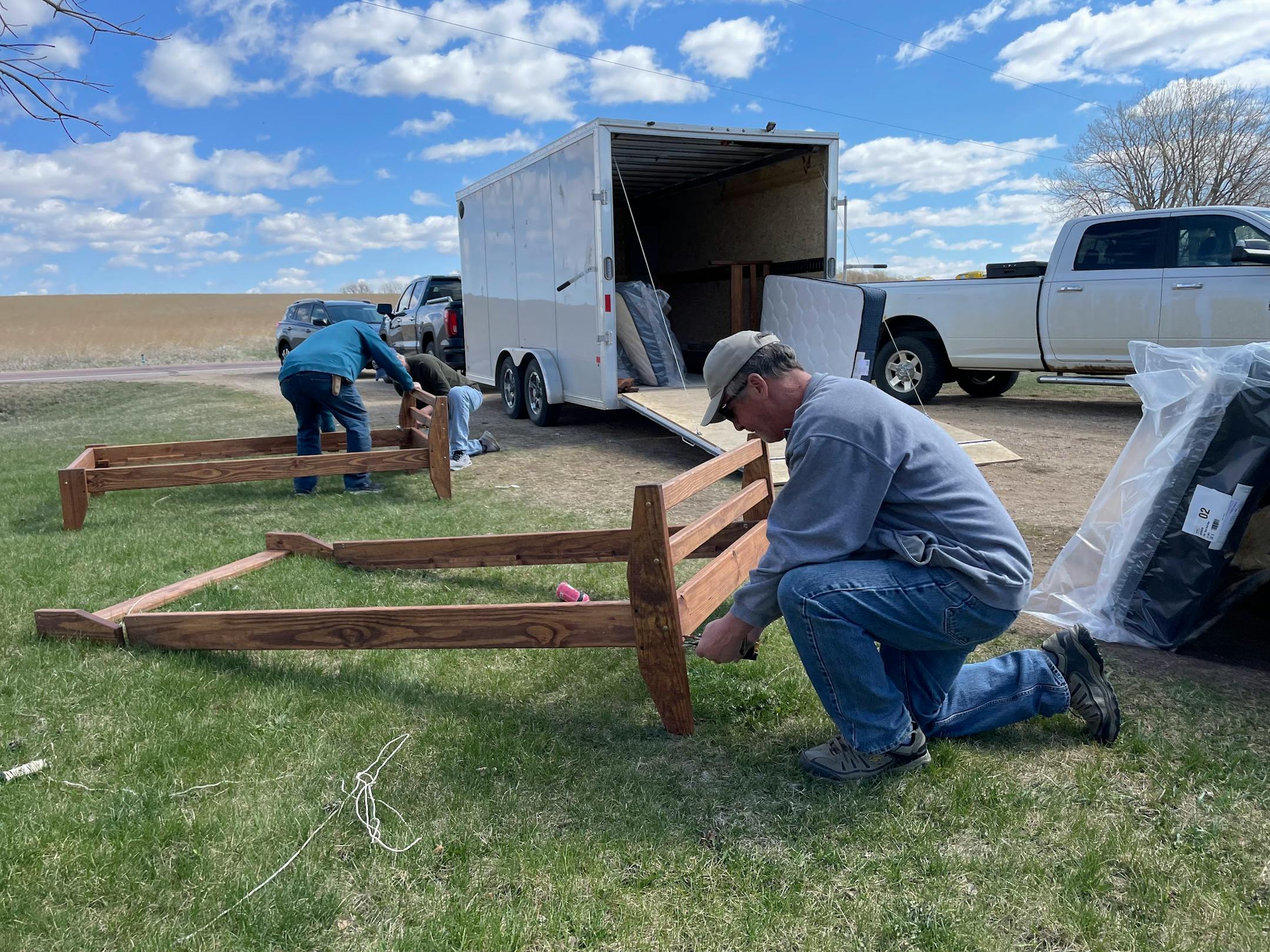 A man assembles a bed frame in front of a moving van.
