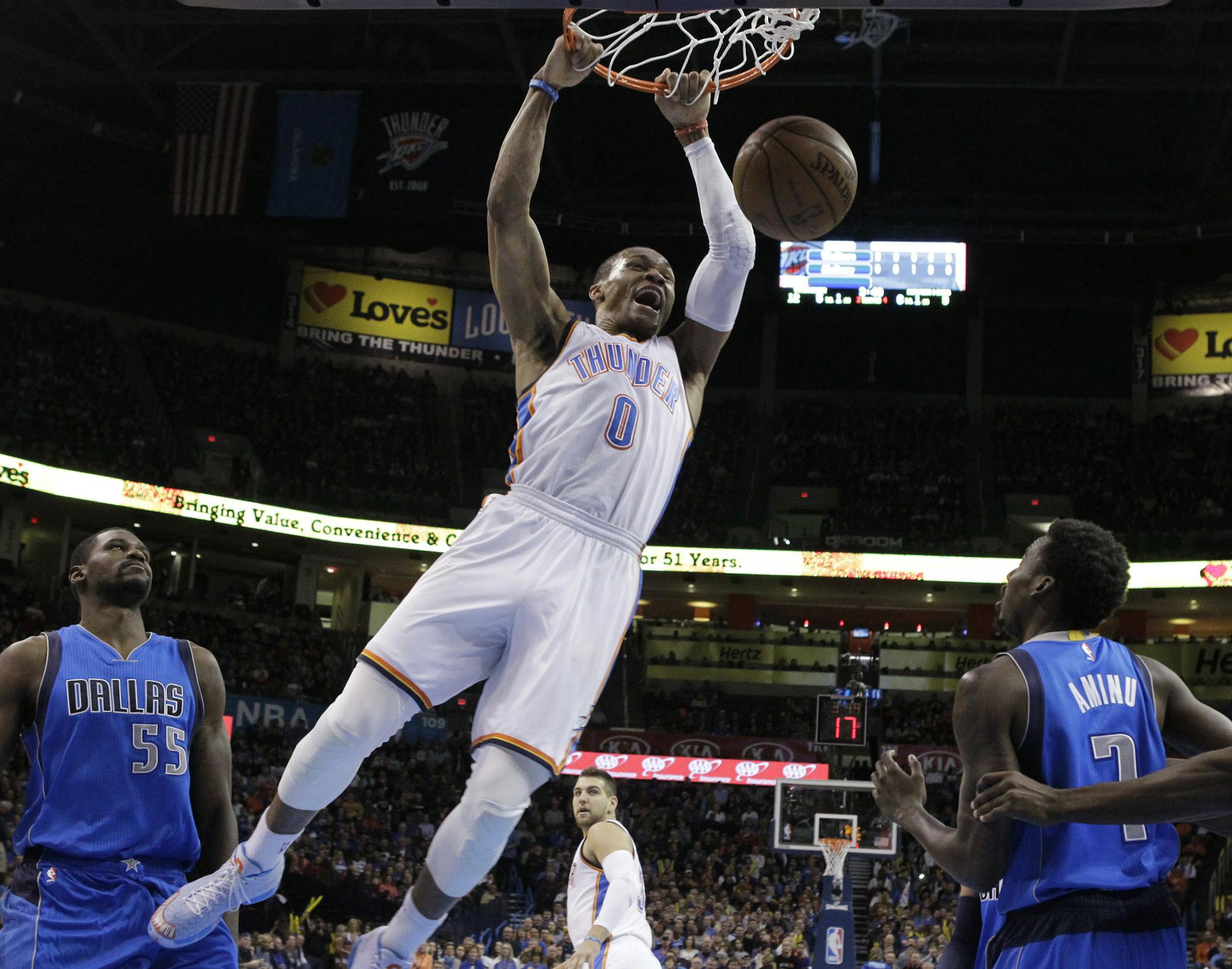 Oklahoma City Thunder guard Russell Westbrook (0) dunks between Dallas Mavericks center Bernard James (55) and Al-Farouq Aminu (7) in the first quarter of an NBA basketball game in Oklahoma City, Thursday, Feb. 19, 2015. (AP Photo/Sue Ogrocki)