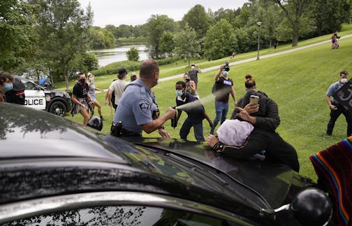 A Minneapolis Parks police officer sprays mace after protestors and homeless advocates blocked the path of a police cruiser attempting to evacuate the area in Powderhorn Park Friday in Minneapolis. Earlier in the morning park officials and police removed the last of the homeless living in the park and had removed most of the tents when protestors charged and pushed the police from the park.] DAVID JOLES • david.joles@startribune.com spot news