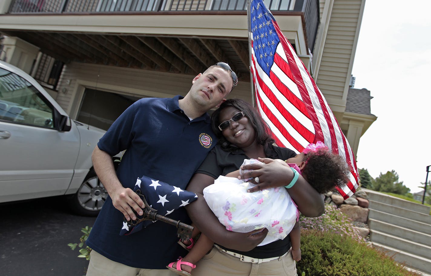 Afghanistan veteran Jason Smith and his wife Trizer Smith and their daughter Imani, 15 months, held a flag and a key to their new home, Thursday, June 26, 2014 in Blaine, MN. Smith was given the key during a ceremony at the Veterans Memorial Park within Bunker Hills Park. The newly renovated mortgage-free home was provided by Chase Bank, AT&T, and the Military Warriors Support Foundation. ] (ELIZABETH FLORES/STAR TRIBUNE) ELIZABETH FLORES &#x2022; eflores@startribune.com