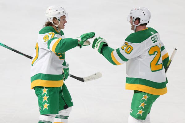 Minnesota Wild's Kirill Kaprizov (97) high-fives teammate Ryan Suter (20) after scoring a goal during the third period of an NHL hockey game against t