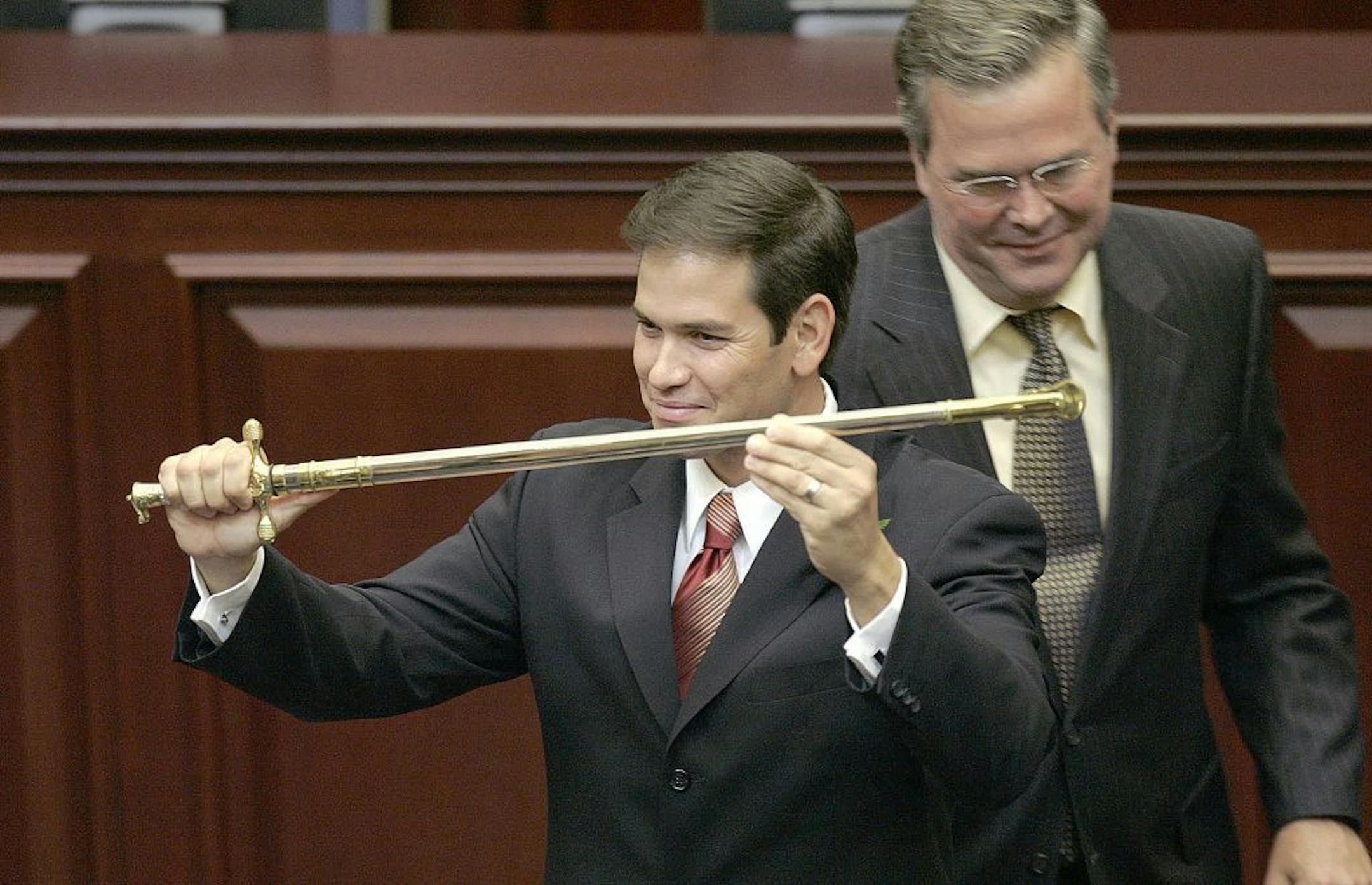 FILE - In this Sept. 13, 2005, file photo, then-Rep. Marco Rubio, R-Miami, left, holds a sword presented to him by then-Gov. Jeb Bush, right, during ceremonies designating Rubio as the next Florida Speaker of the House in Tallahassee, Fla. Devoted political allies for more than a decade, the alliance between Bush and Rubio is beginning to splinter as the one-time mentor and his political prot�g� face off in the race for the Republican presidential nomination.