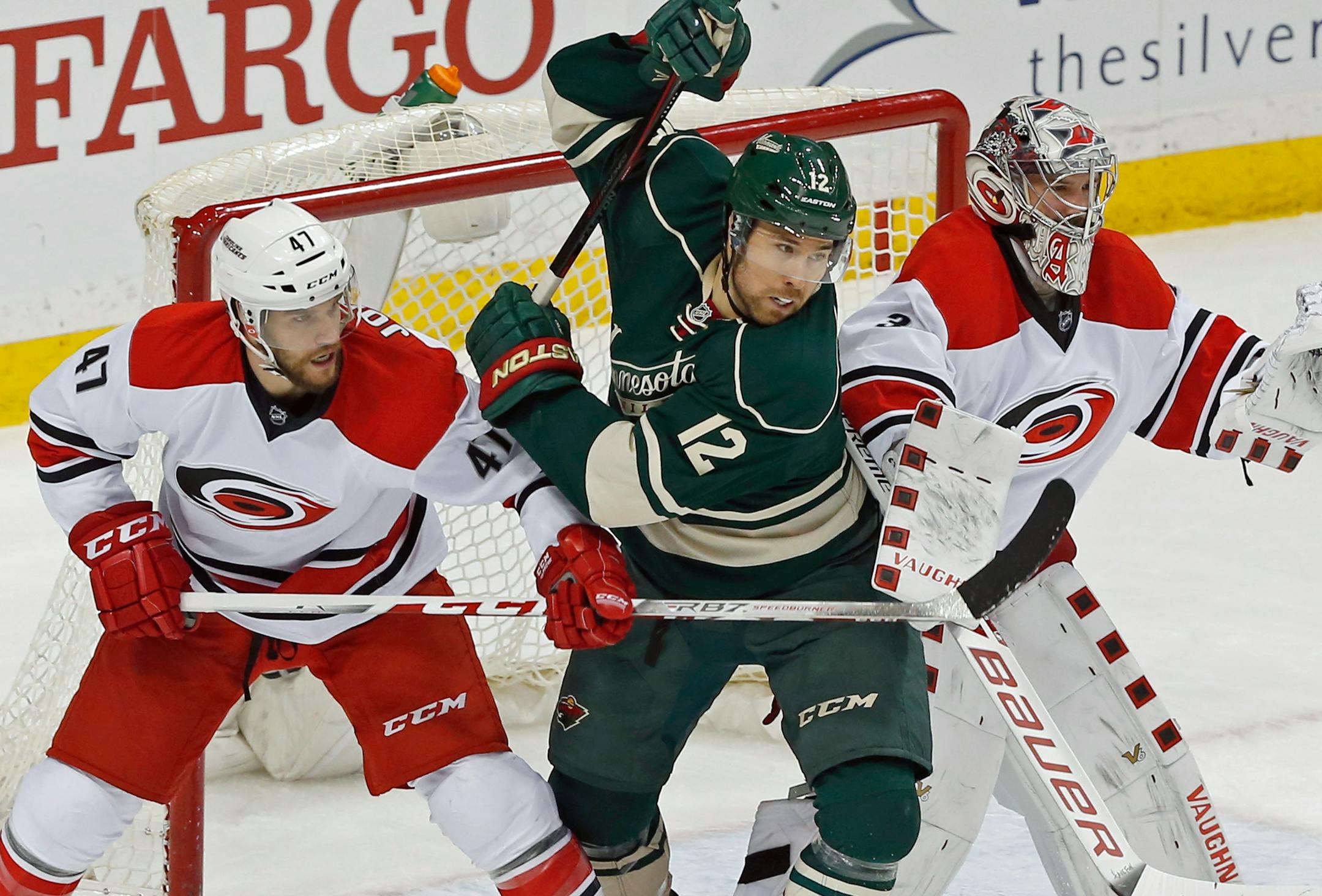 Minnesota Wild's David Jones, center, tries to break free from Carolina Hurricanes' Michal Jordan, left, of the Czech Republic as Cam Ward, right, minds the net in the first period of an NHL hockey game Saturday, March 19, 2016, in St. Paul, Minn. (AP Photo/Jim Mone)