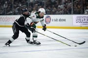 Wild defenseman Brock Faber fights off Kings winger Adrian Kempe to control the puck during Monday night's game in Los Angeles.