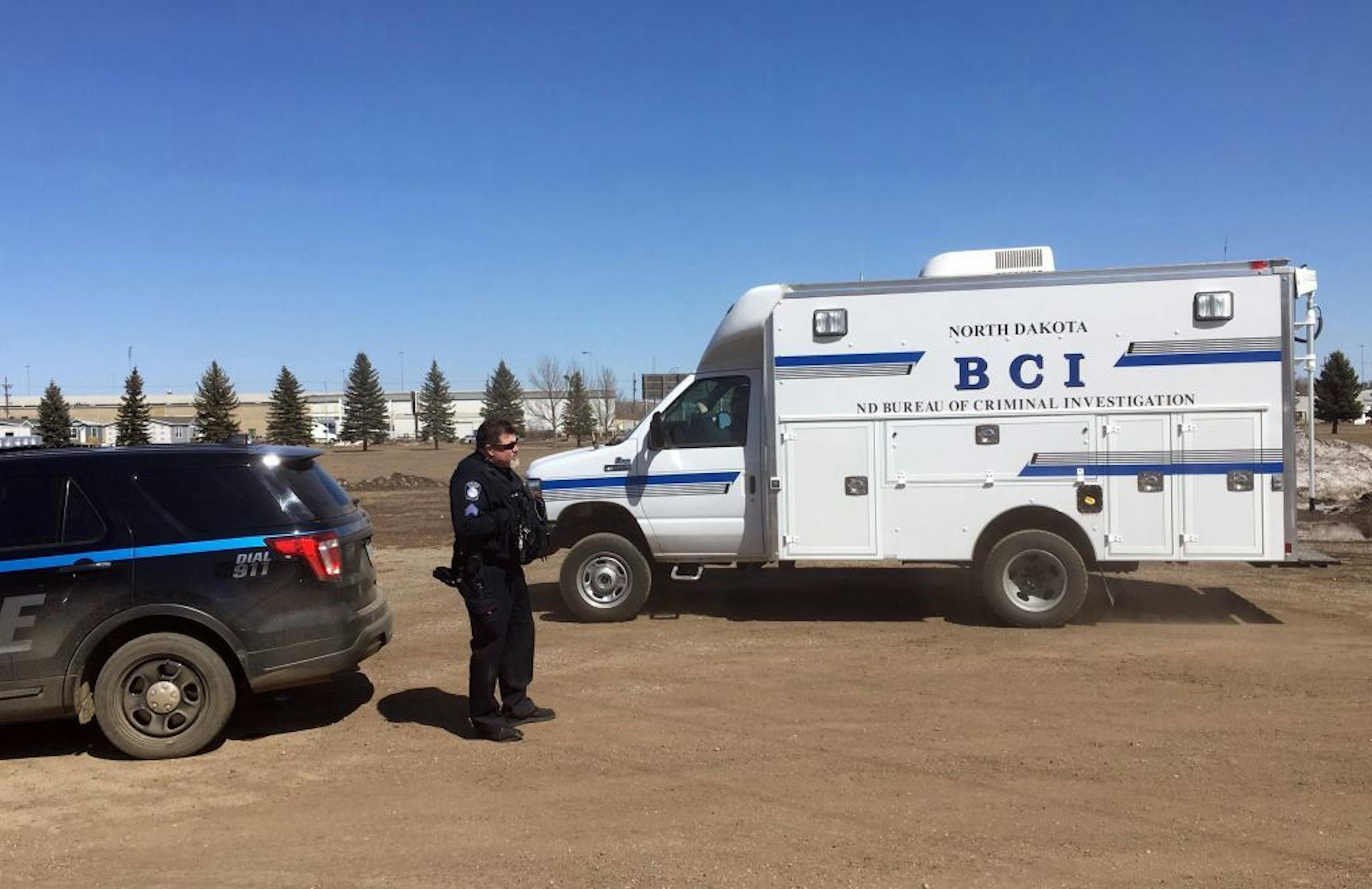 In this Wednesday, April 3, 2019 photo, state and local police search a field in Manton, N.D., about half a mile from a business where an owner and three employees were found dead. Authorities on Thursday said they were looking for "potential evidence" related to the deaths discovered Monday at RJR Maintenance and Management in Mandan, a city just outside Bismarck. Police haven't yet identified a suspect.