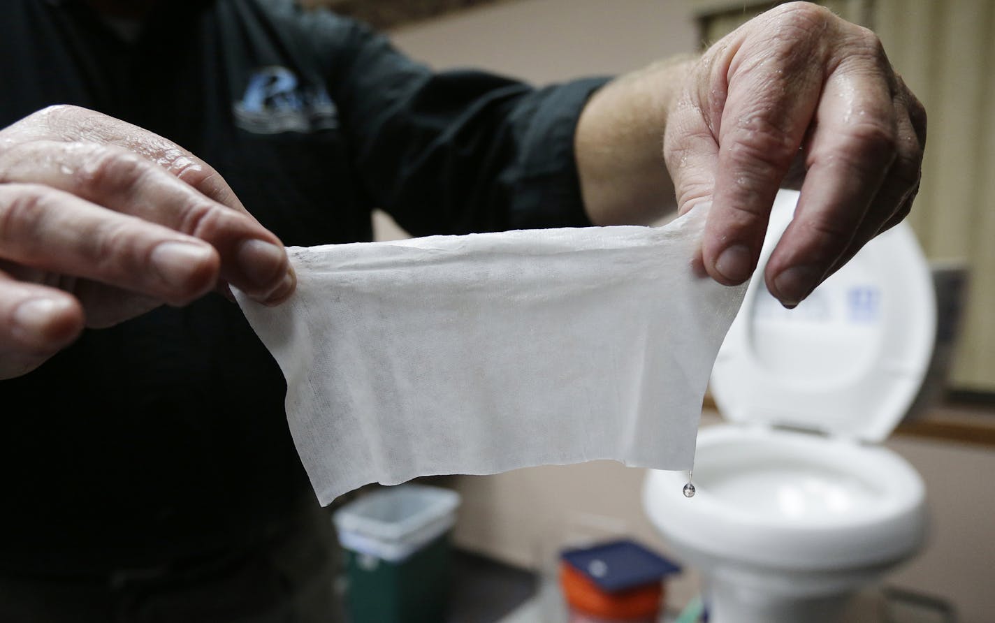 In this photograph taken, Friday, Sept. 20, 2013, in Middlesex, N.J., Rob Villee, executive director of the Plainfield Area Regional Sewer Authority in New Jersey, holds up a wipe he flushed through his test toilet in his office. Increasingly popular bathroom wipes, thick, premoistened towelettes that are advertised as flushable, are creating clogs and backups in sewer systems around the nation. The problem has gotten so bad in this upstate New York town that frustrated sewer officials traced th