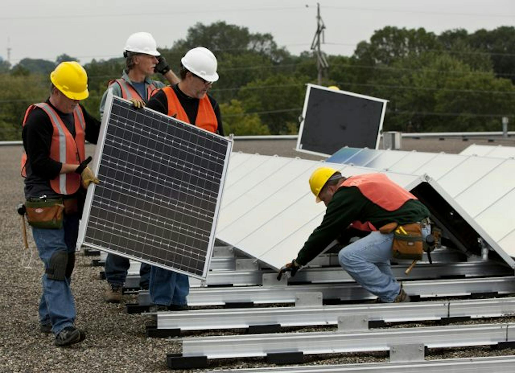 Workers set up solar arrays by TenKsolar on a Murphy Warehouse roof. This is believed to be the first big local solar installation on a flat roof.