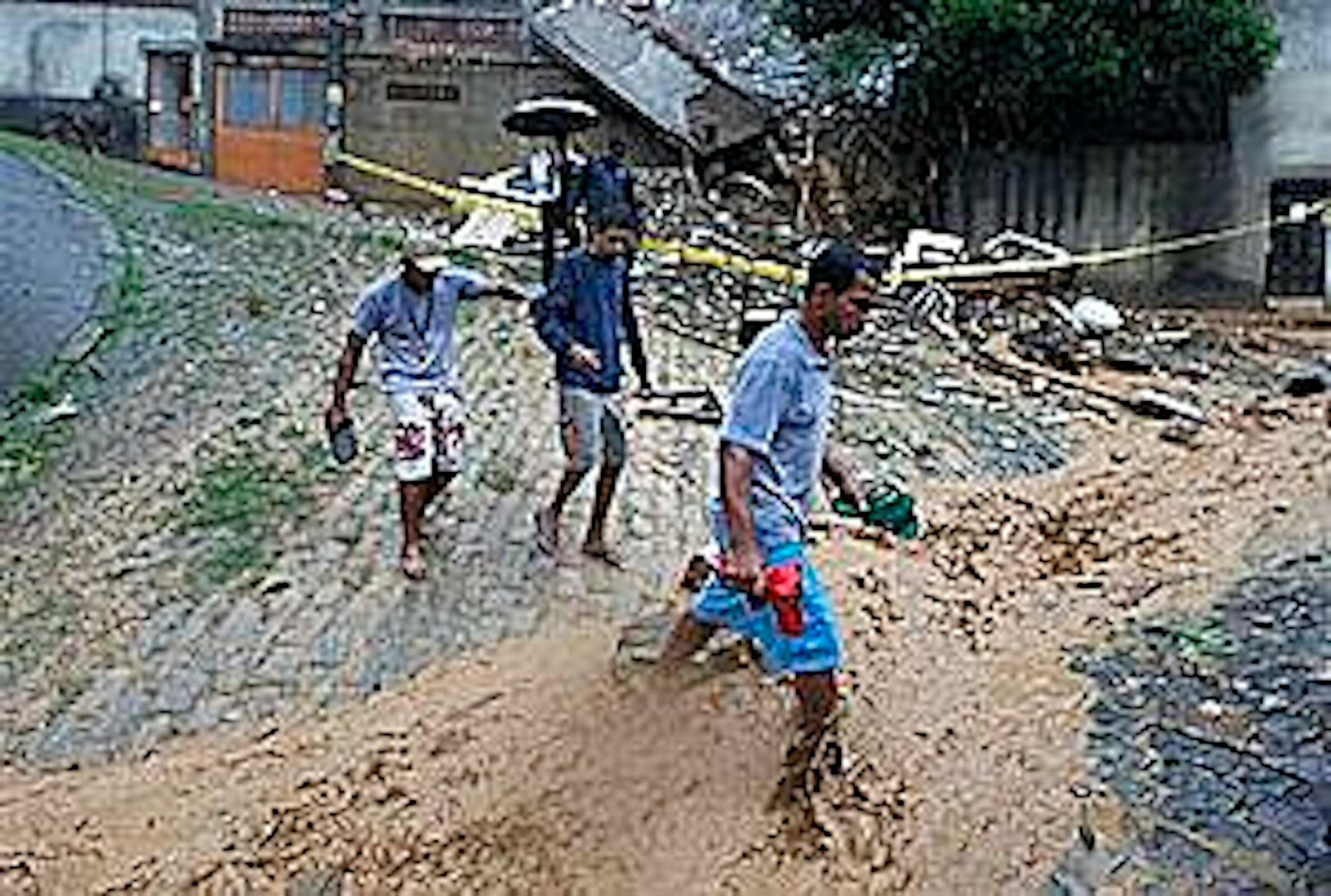 People cross a flooded street in the Morro dos Prazeres area of the Santa Teresa neighborhood in Rio de Janeiro, Tuesday, April 6, 2010. Landslides triggered by torrential rains, killed at least 81 people as rising water inundated Brazil's second-largest city, turning roads into rivers and paralyzing almost all aspects of city life. (AP Photo/Felipe Dana)