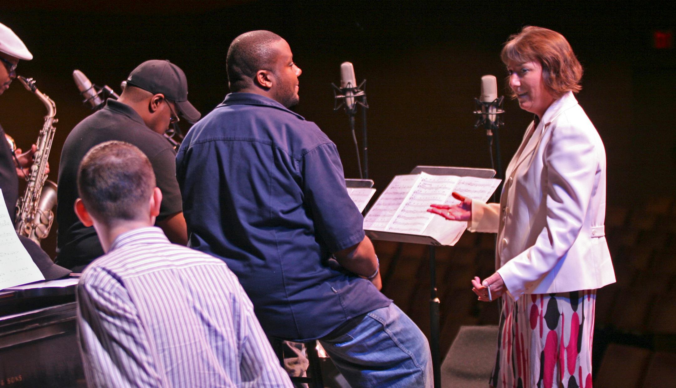 Lilly Schwartz ( right) greets Sean Jones ( center/blue shirt) and members of the " DownBeat's Rising Stars " ensemble when they arrived to rehearse at Orchestra Hall before an evening performance. Schwartz is the new directoer of non-classical music.