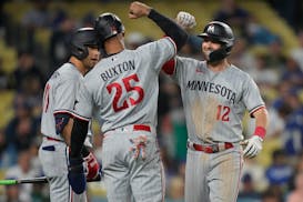 Kyle Farmer (12) celebrates with designated hitter Byron Buxton (25) after they both scored off of a home run hit by Farmer during the ninth inning.