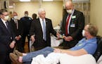 Vice President Mike Pence, center, visits a patient who survived the coronavirus and was going to give blood during a tour of the Mayo Clinic Tuesday,