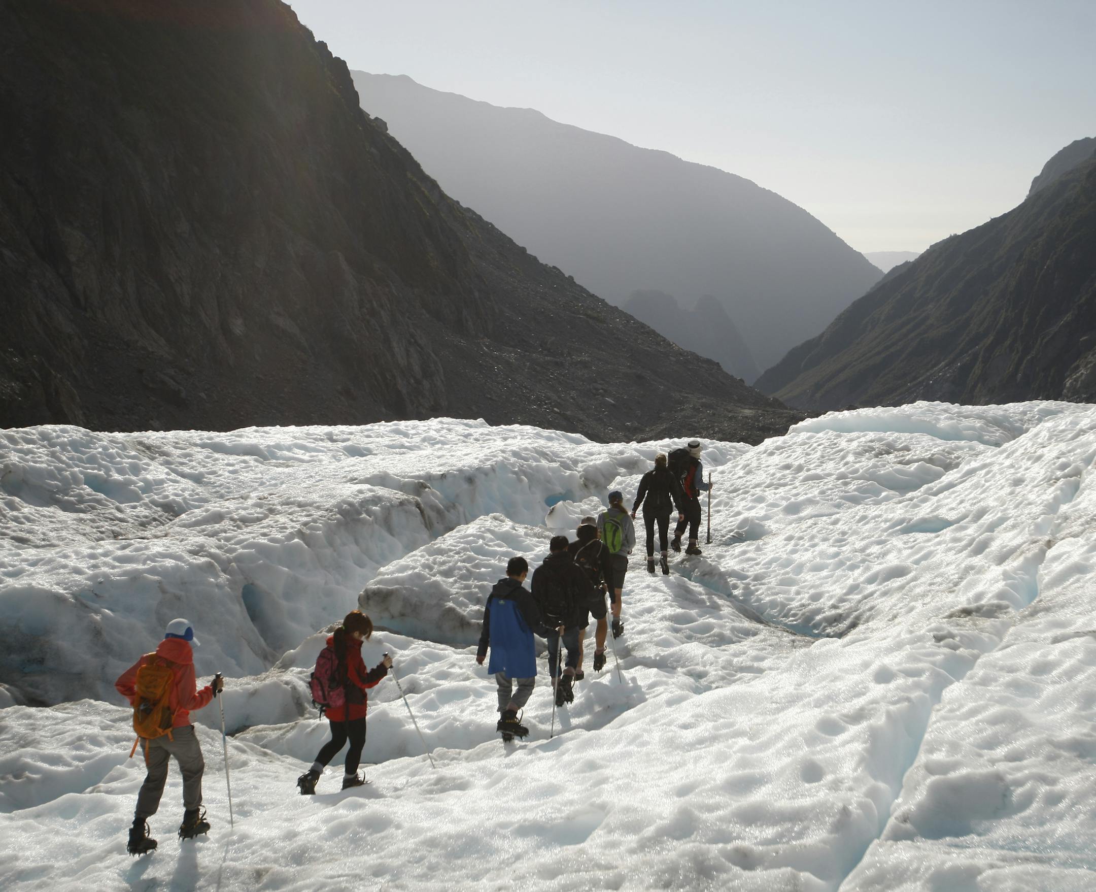 In this Feb. 6, 2016 photo, tourists who have taken a helicopter trip onto the Fox Glacier follow a guide in New Zealand. The Fox and Franz Josef glaciers have been melting at such a rapid rate that it has become too dangerous for tourists to hike onto them from the valley floor, ending a tradition that dates back a century. (AP Photo/Nick Perry)