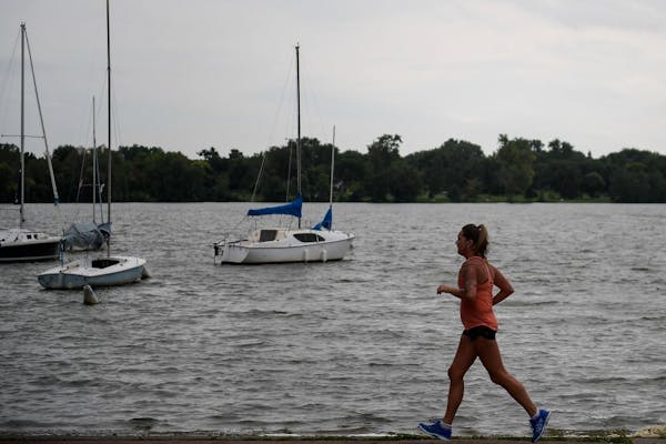 A runner jogs past a boat launch area near the main beach of Lake Nokomis Friday afternoon.