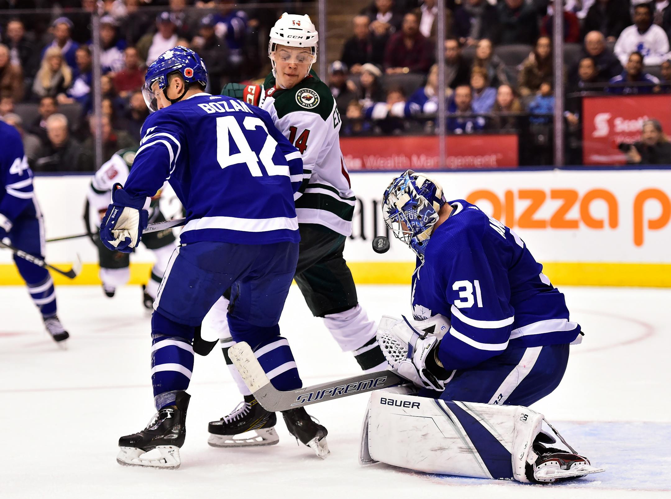 Toronto Maple Leafs goalie Frederik Andersen (31) makes a save near teammate Tyler Bozak (42) and Minnesota Wild center Joel Eriksson Ek (14) during the third period of an NHL hockey game Wednesday, Nov. 8, 2017, in Toronto. (Frank Gunn/The Canadian Press via AP)