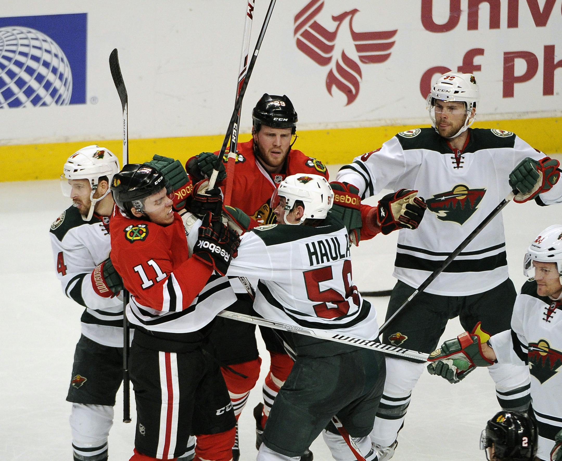 Chicago Blackhawks' Jeremy Morin (11) and Minnesota Wild's Erik Haula (56) get into an altercation in the second period of an NHL hockey game in Chicago, Thursday, April 3, 2014. (AP Photo/David Banks)