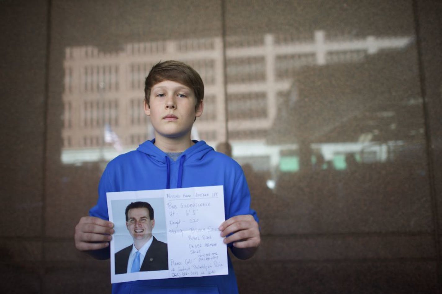 Marc Gildersleeve, 13, of Baltimore, holds a poster he made of his still missing father from Amtrak 188 in Philadelphia, May 13, 2015. Bob Gildersleeve was a passenger on the train carrying more than 200 passengers from Washington, DC to New York which derailed Tuesday in north Philadelphia, killing at least seven people.