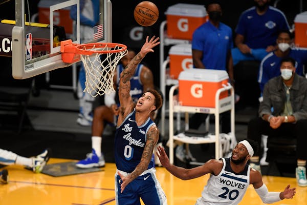 Los Angeles Lakers forward Kyle Kuzma, left, shoots past Minnesota Timberwolves guard Josh Okogie during the first half of an NBA basketball game in L