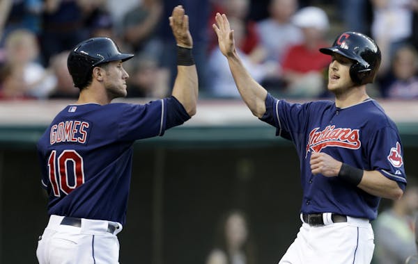 Cleveland Indians' Yan Gomes, left, and Drew Stubbs high-five after both scored on a triple by Jason Kipnis against the Twins on Friday