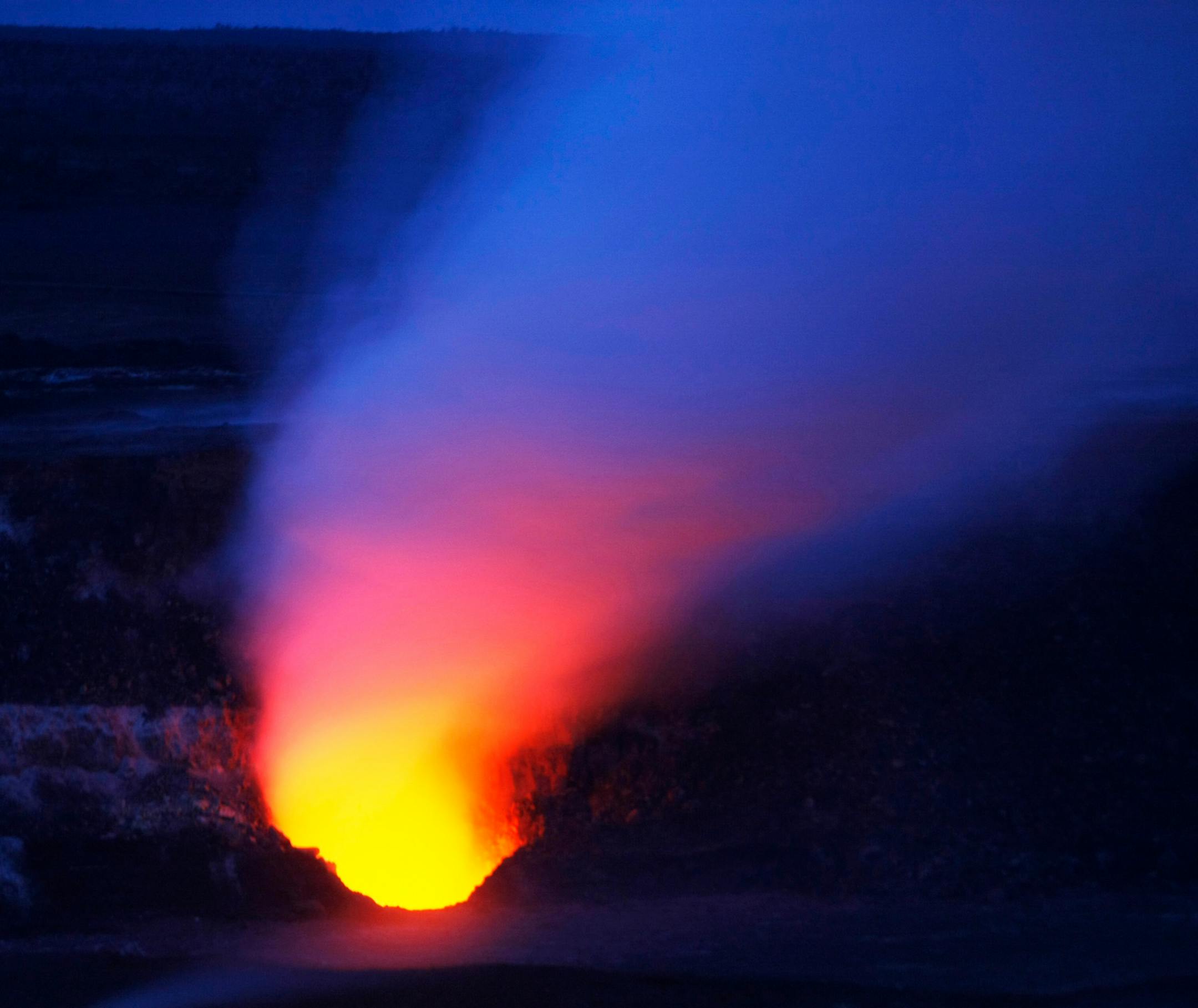 In the early hours before dawn, the Halema'uma'u vent can be seen glowing in the darkness. The vent is emitting dangerous plumes of sulfur dioxide causing part of the Crater Rim Drive loop to be closed.