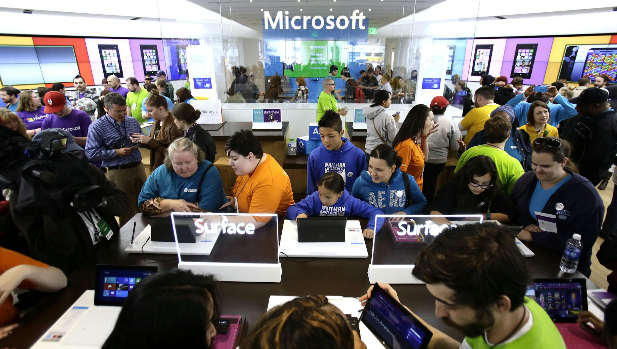 In this Thursday, June 20, 2013, photo, people crowd the aisles during the grand opening of a Microsoft retail store in downtown Portland, Ore. Microsoft Corp. reports quarterly financial results after the market closes on July, 18, 2013. (AP Photo/Don Ryan)