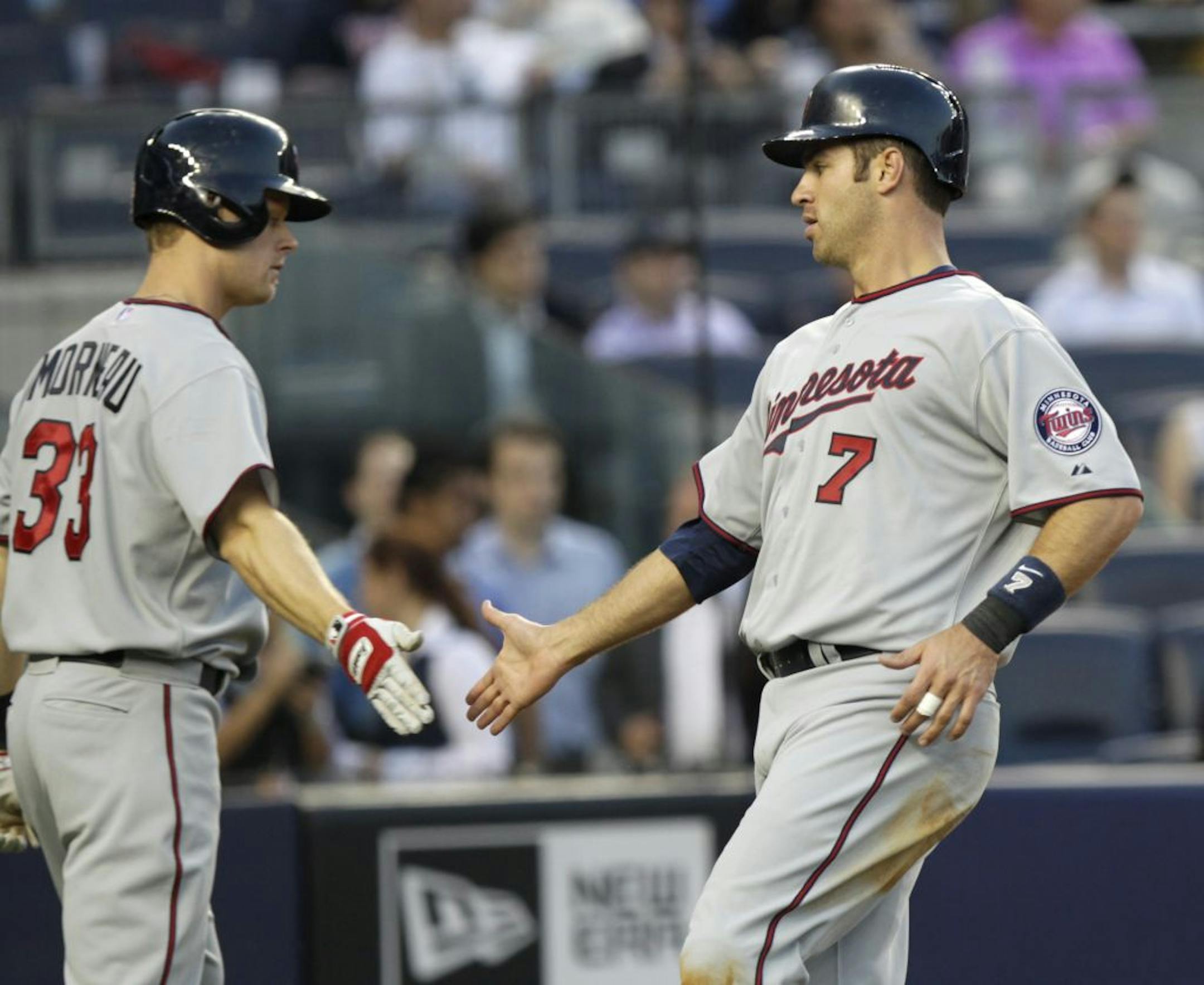 Minnesota Twins' Joe Mauer, right, is greeted by Justin Morneau after Mauer scored on a single by Josh Willingham during the first inning of a baseball game against the New York Yankees at Yankee Stadium in New York, Monday, April 16, 2012.