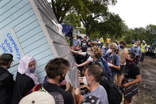 Protesters and homeless advocates turned a community library building on its side to try to salvage it after people living in Powderhorn Park in Minneapolis were removed Aug. 14.