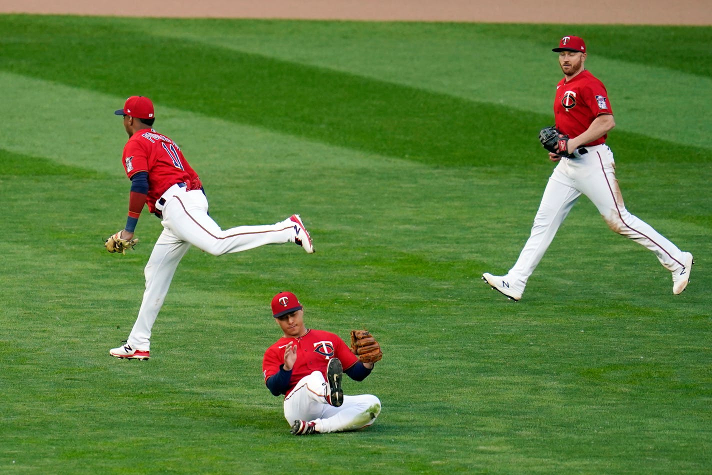 Minnesota Twins center fielder Rob Refsnyder, center, makes a catch after he, second baseman Jorge Polanco, left, and right fielder Kyle Garlick converged to rob Kansas City Royals' Adalberto Mondesi of a hit in the fourth inning of a baseball game, Friday, May 28, 2021, in Minneapolis. (AP Photo/Jim Mone)