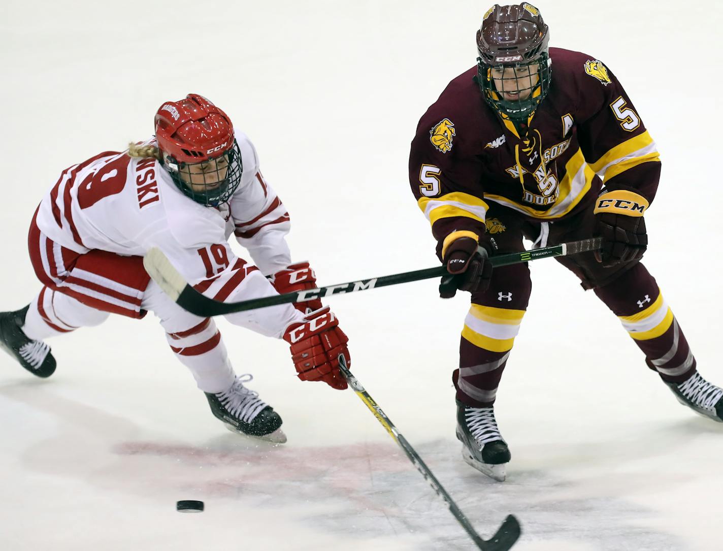 Annie Pankowski(19) fights for the puck against Sidney Morin(5).] UMD women's hockey in WCHA Final against Wisconsin in championship game at Ridder Arena. RICHARD TSONG-TAATARII • richard.tsong-taatarii@startribune.com