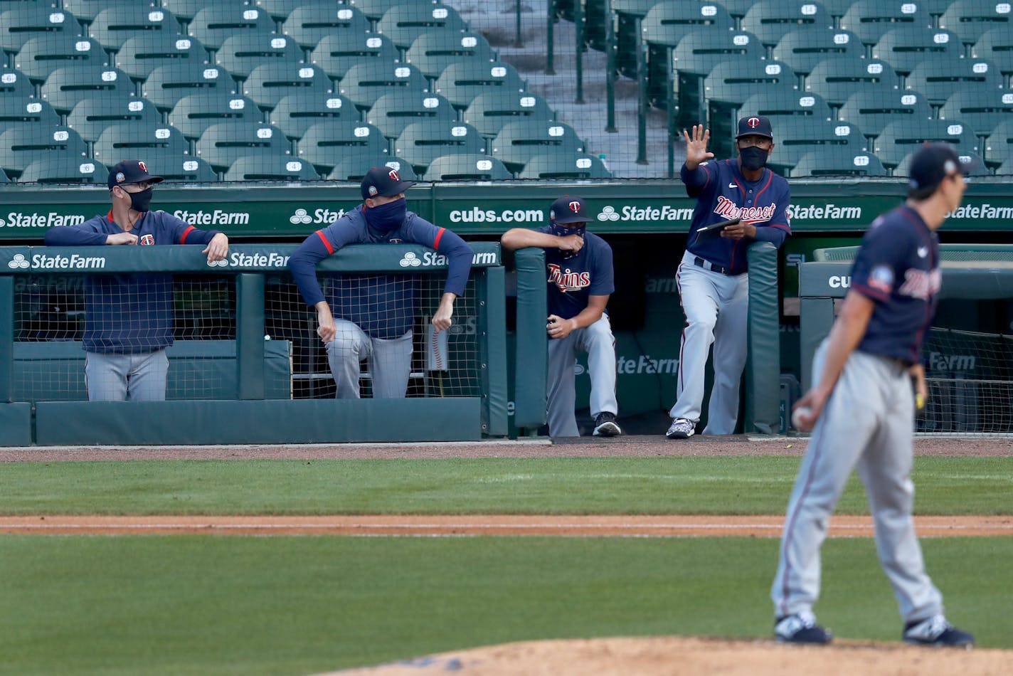 The Twins' coaching staff positions a fielder from the dugout during the second inning of a summer camp game against the Cubs