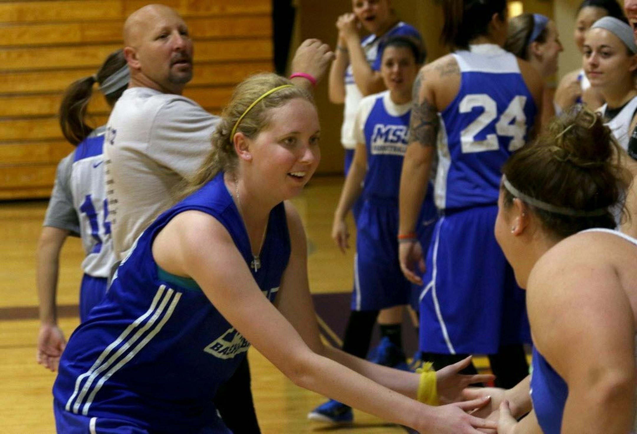 Lauren Hill, left foreground, slaps hands with teammates as she practices with her NCAA college basketball team at Mount St. Joseph in Cincinnati on Thursday Oct. 23, 2014.