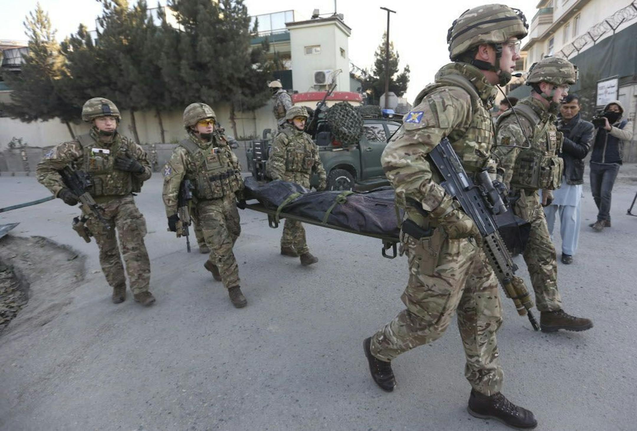 British soldiers carry the dead body of a victim in an attack happened near Spanish Embassy in Kabul, Afghanistan, Saturday, Dec. 12, 2015. Explosions and gunfire rocked a diplomatic area of central Kabul overnight as security forces tried to flush out Taliban attackers who claimed responsibility for a deadly car bomb Friday.
