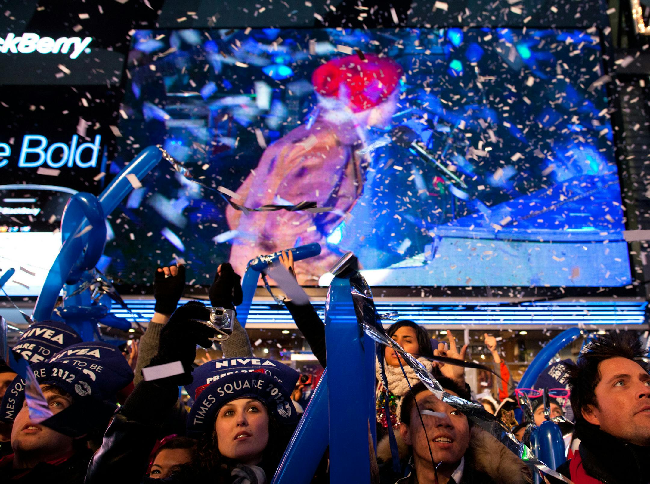 Revelers are showered in confetti in Times Square in anticipation of midnight on New Years Eve, Saturday, Dec. 31, 2011, in New York. Some revelers, wearing party hats and "2012" glasses, began camping out Saturday morning, as workers readied bags stuffed with hundreds of balloons and technicians put colored filters on klieg lights. (AP Photo/John Minchillo)