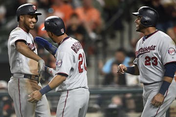 Minnesota Twins Jonathan Schoop, left, is congratulated by Eddie Rosario, center, and Nelson Cruz after hitting a three-run home run against the Balti