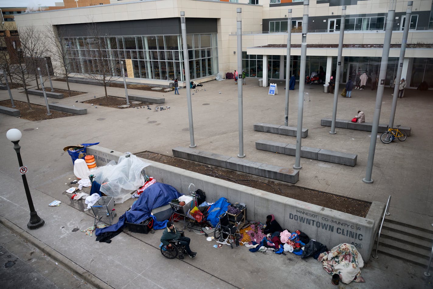 People bundle up under tarps and blankets in freezing temperatures Friday, Jan. 12, 2024 outside the Dorothy Day Opportunity Center in St. Paul, Minn.. Twin Cities nonprofits are opening their doors to provide shelter to those who need a place to keep warm as the first cold snap of the season arrives this weekend.