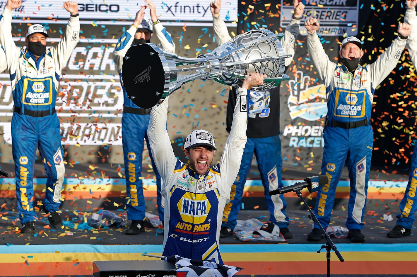 Chase Elliott holds up the season championship trophy as he celebrates with his race crew in Victory Lane