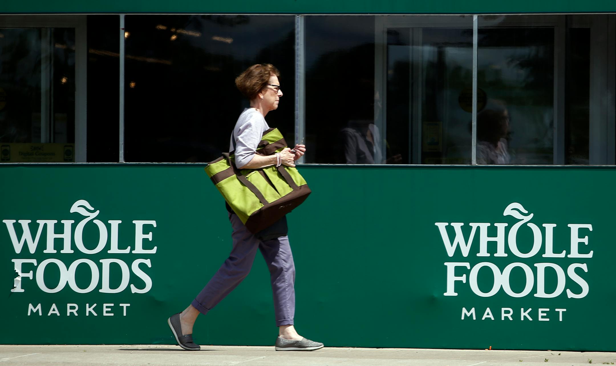 A shopper leaves a Whole Foods Market in Northbrook, Ill., Saturday, June 17, 2017. Amazon is buying Whole Foods in a deal valued at about $13.7 billion, a strong move to expand its growing reach into groceries. (AP Photo/Nam Y. Huh)