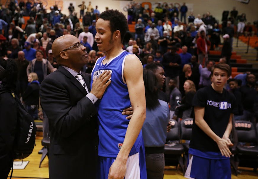 Amir Coffey of Hopkins celebrates with assistant coach Kerry Sutherland, left, after their win against Robbinsdale Cooper.