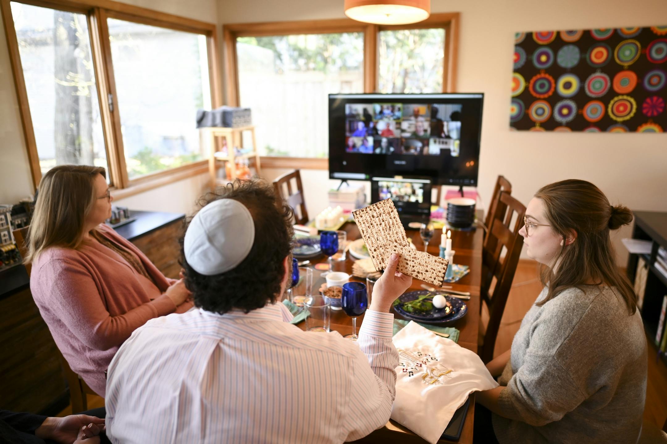 Bruce Manning held up matzo, which he just broke in half as part of Passover seder ritual, as he took part in a virtual seder alongside his family Wednesday night.