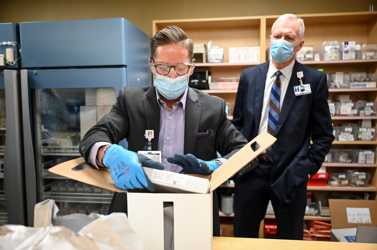 Paul Krogh, director of pharmacy services for North Memorial Health Hospital, unboxed the 975 doses of the Pfizer COVID-19 vaccine that arrived early Tuesday morning at the hospital. To his right was Dr. Kevin Croston, CEO of North Memorial