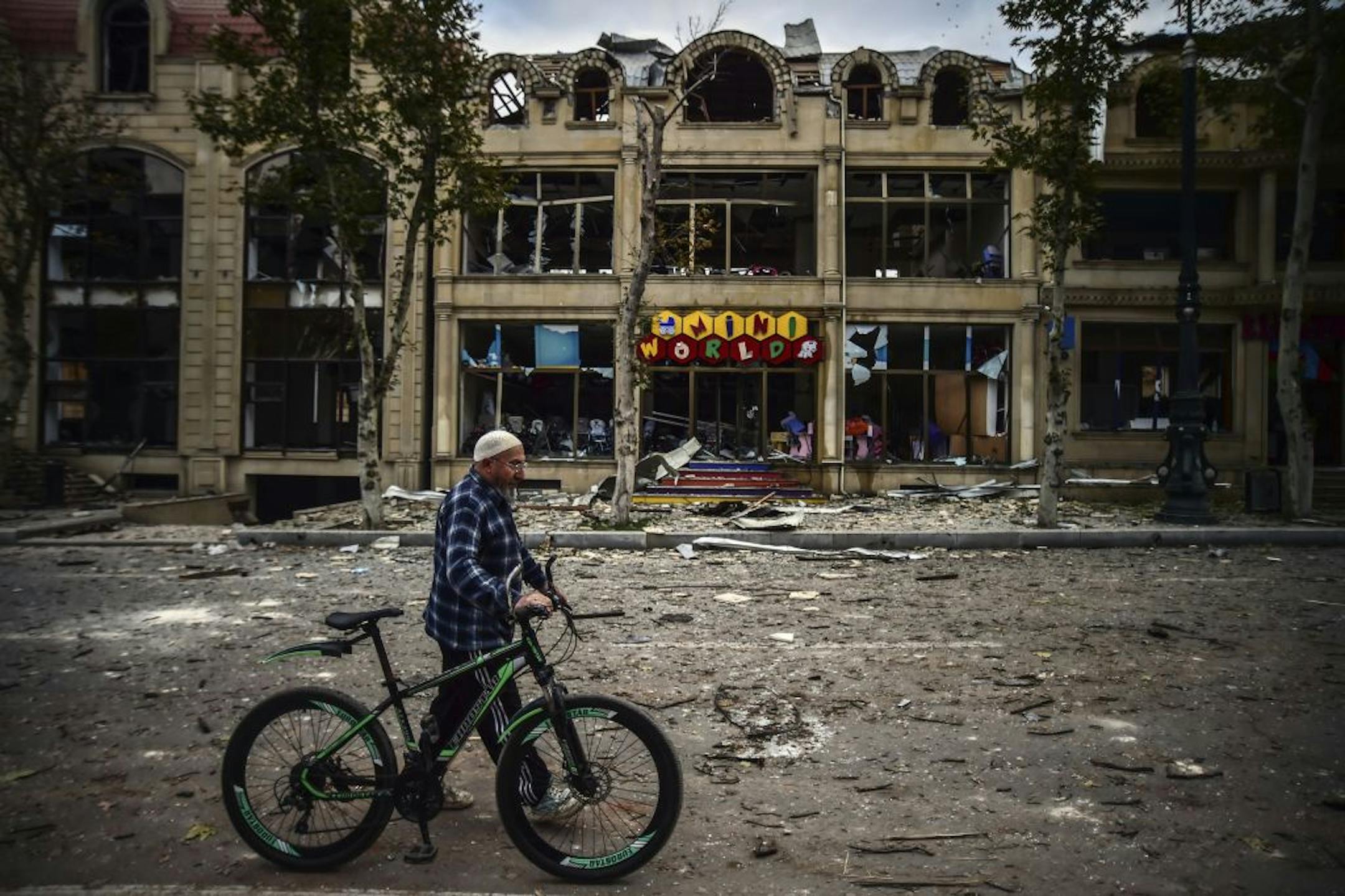 A man walks past a damaged building in a residential area in Ganja, Azerbaijan's second largest city, near the border with Armenia, after rocket fire overnight by Armenian forces, early Sunday, Oct. 11, 2020. Several civilians were killed and dozens were wounded. Russian President Vladimir Putin brokered a cease-fire on Friday in a series of calls with President Ilham Aliyev of Azerbaijan and Armenia's Prime Minister Nikol Pashinian.
