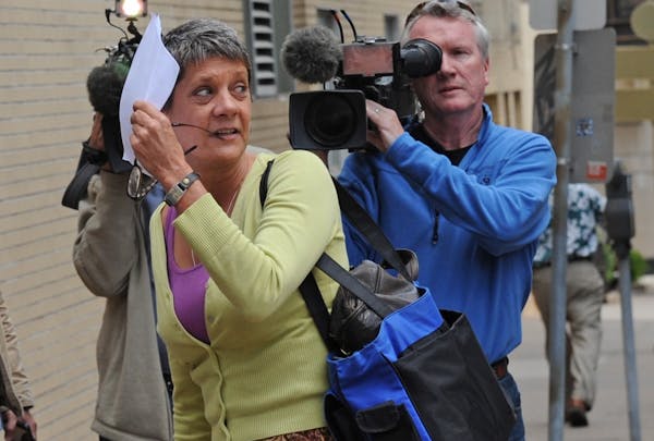 Lori Christensen tried to hide from the news media behind a sheet of paper.