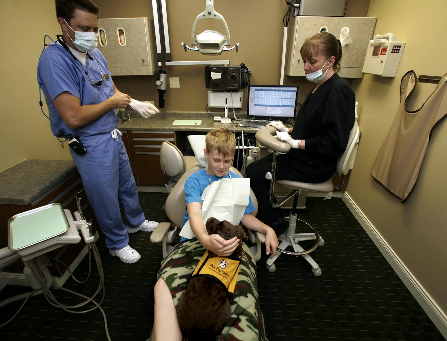 Patient Hugh Witzmann of Maplewood pets Molly (dog) as Dr. Brian Kraby and Mary Reck prepare to fill a cavity at Applewood Family Dental in Woodbury, MN on August 13, 2013. ] JOELKOYAMA&#x201a;&#xc4;&#xa2;joel koyama@startribune