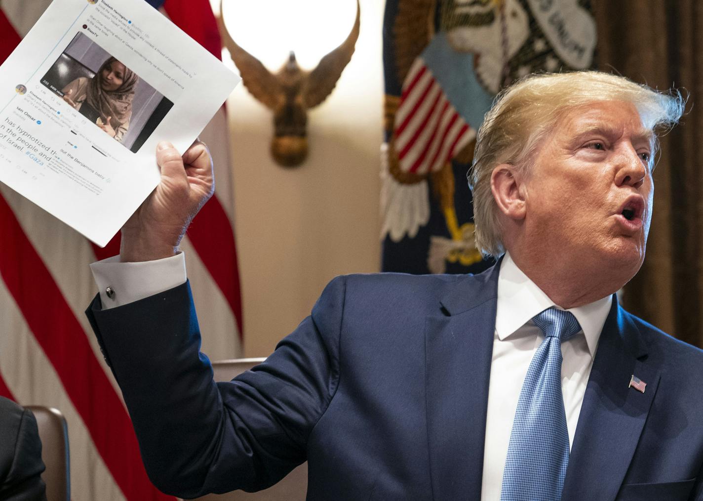 President Donald Trump held up a photo of Rep. Ilhan Omar during a meeting at the White House in Washington on Tuesday, hours before a House vote to condemn Trump's weekend tweets and comments about Omar and three of her colleagues.