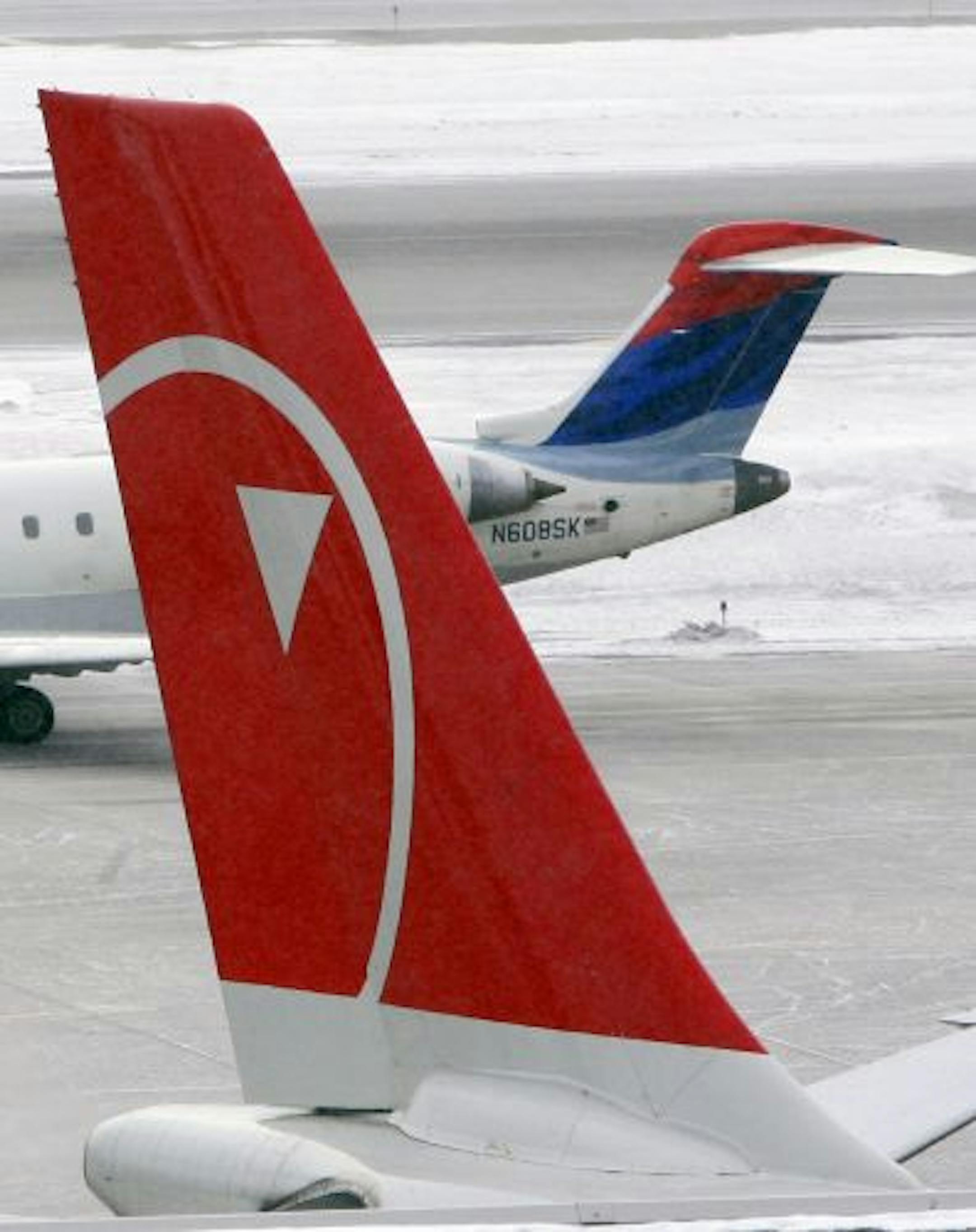 Corporate colors are on a Delta Connection plane that taxis in the background behind a parked Northwest Airlines plane Tuesday, Feb. 19, 2008 at the Minneapolis-St. Paul International Airport in Minneapolis. The boards of directors of Delta Air Lines Inc. and Northwest Airlines Corp. were expected to vote Wednesday on a combination provided their pilot unions can reach their own integration deal by then, people briefed on the discussions said Tuesday.