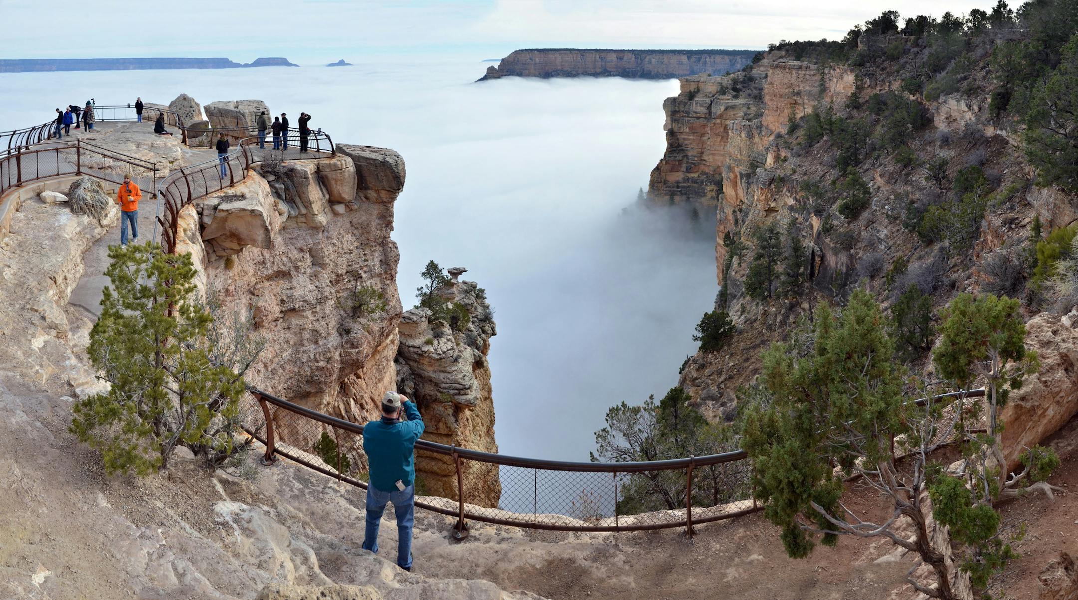 In this photo provided by the National Park Service, visitors to Mather Point on the South Rim of Grand Canyon National Park, in Ariz., view a rare weather phenomenon - a sea of thick clouds filling the canyon just below the rim, Thursday, Dec. 11, 2014. The total cloud inversion is expected to hang inside the canyon throughout Thursday. Cory Mottice of the National Weather Service said the weather event happens about once every several years, though the landmark was treated to one last year. (A