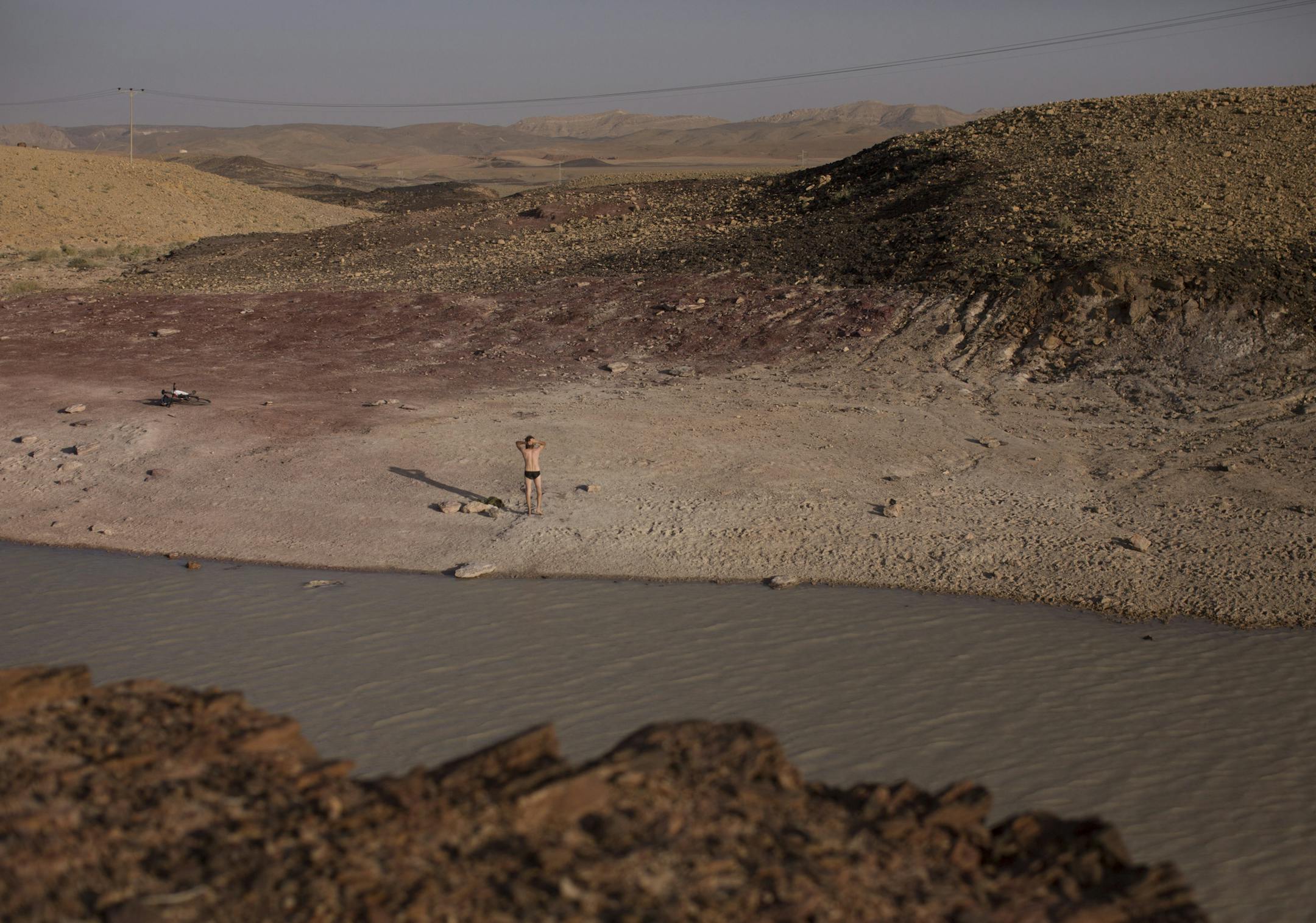 A man stands near a rain water pool at the Ramon Crater, in the Negev desert in Israel, April 29, 2015. With its part-Mediterranean, part-desert climate, Israel had suffered from chronic shortages and exploitation of its natural water resources for decades, but a national effort to desalinate Mediterranean seawater and to recycle wastewater has provided Israel with enough water for all its needs. (Uriel Sinai/The New York Times)