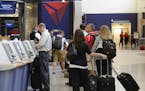 In this Friday, Sept. 27, 2013 photo, Delta Air Lines passengers line up to check luggage at Hartsfield-Jackson Atlanta International Airport, in Atla